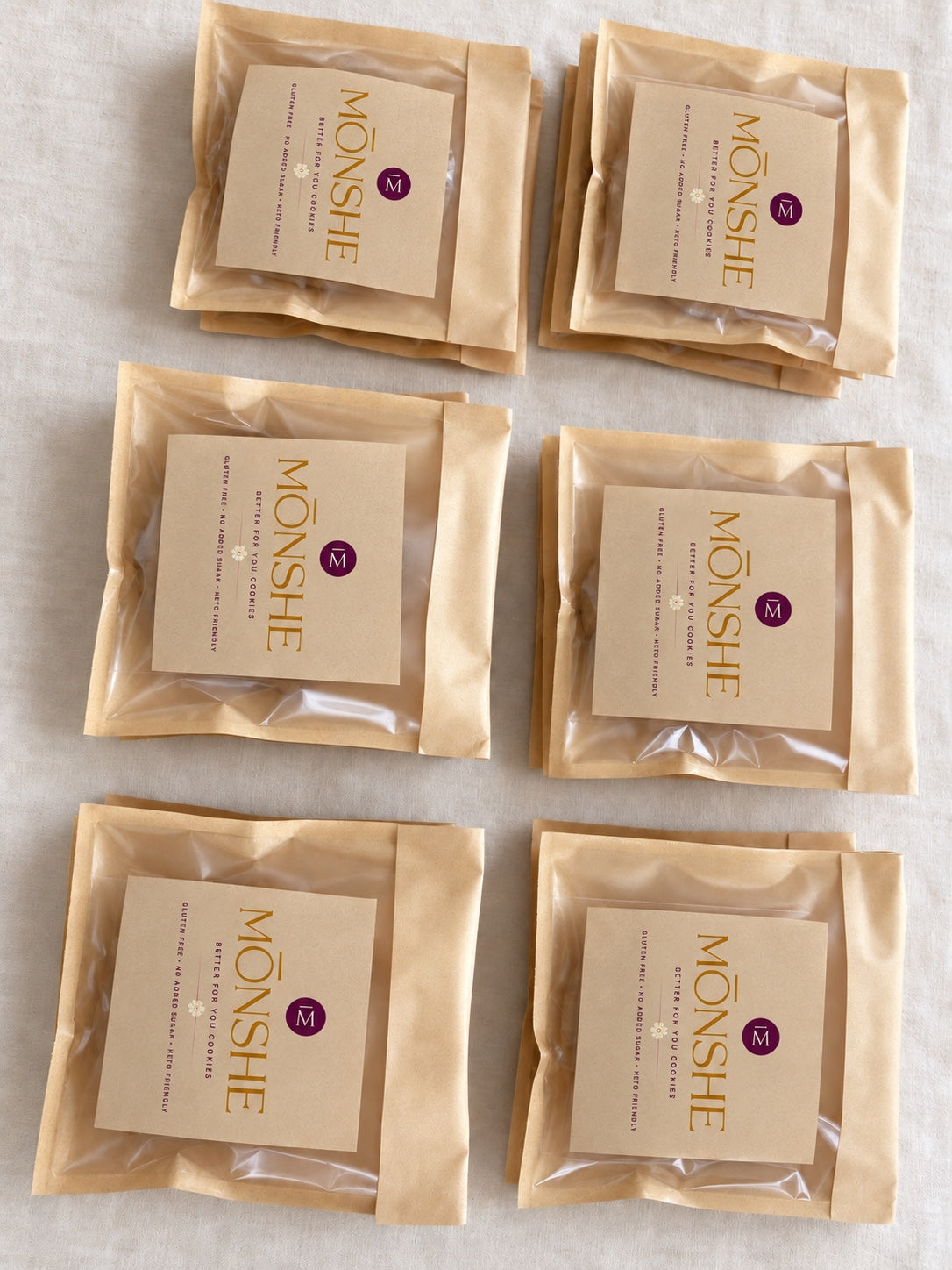 Six individually wrapped Monshe cookies in branded kraft pouches